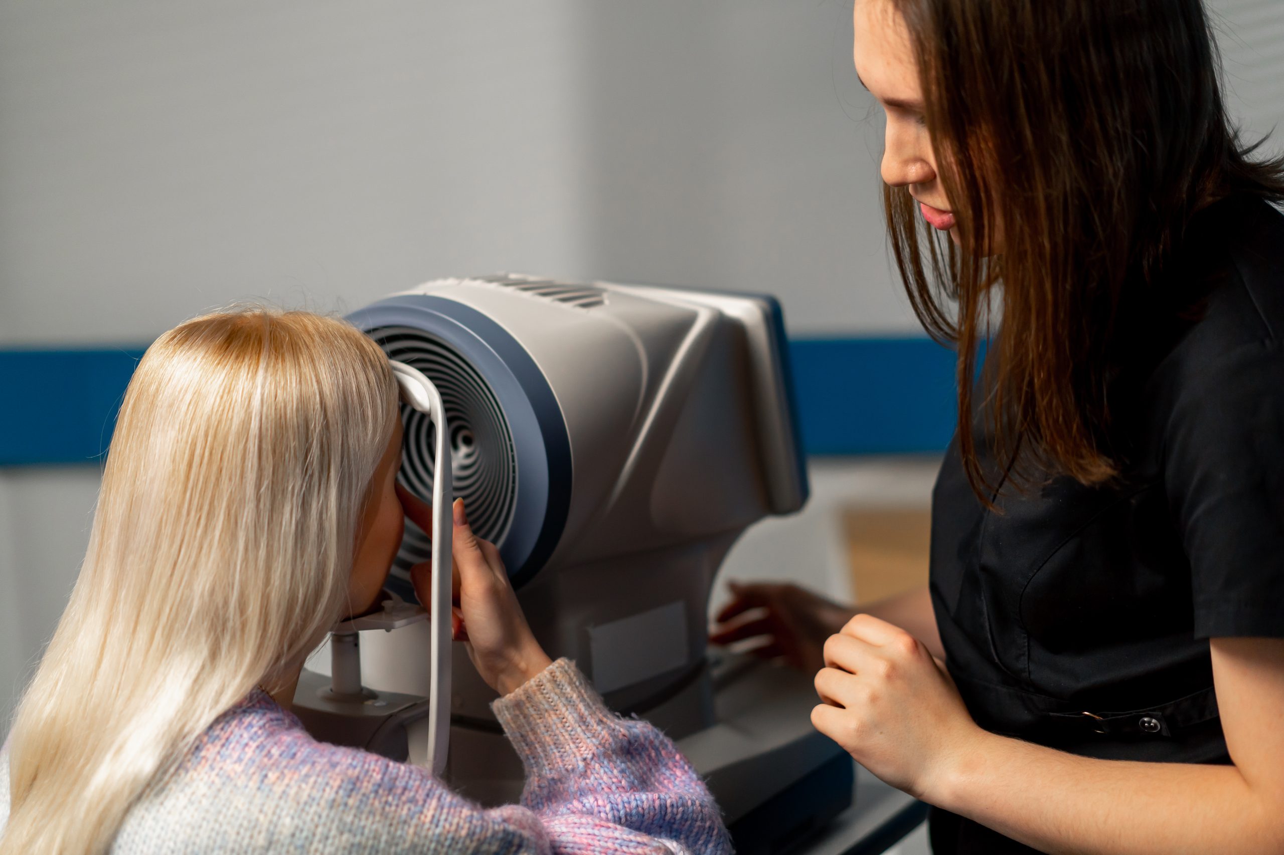 close up in an ophthalmology clinic woman doctor shows a girl with her finger how to tighten the skin under the eye